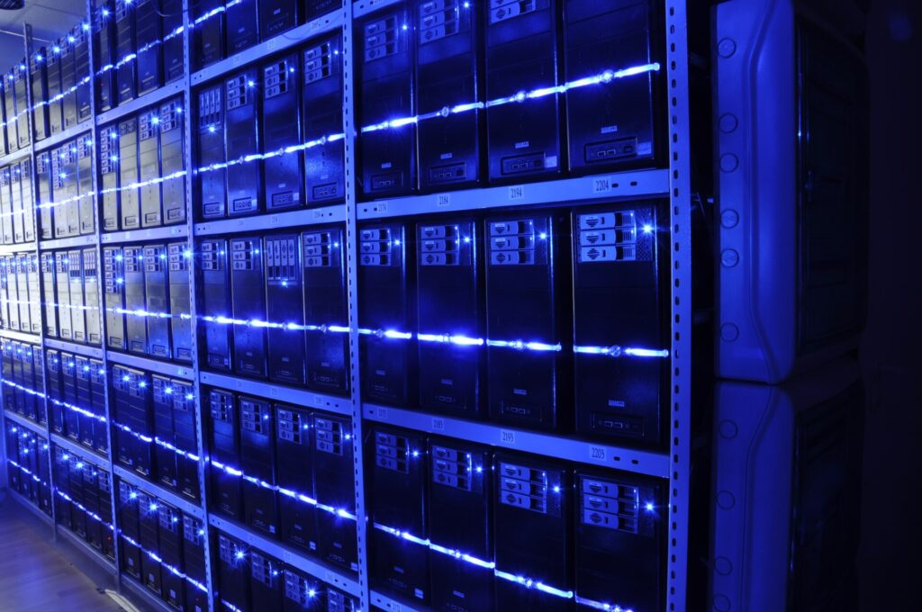 Corridoio di una sala macchine con armadi di server accesi e spie luminose allineate