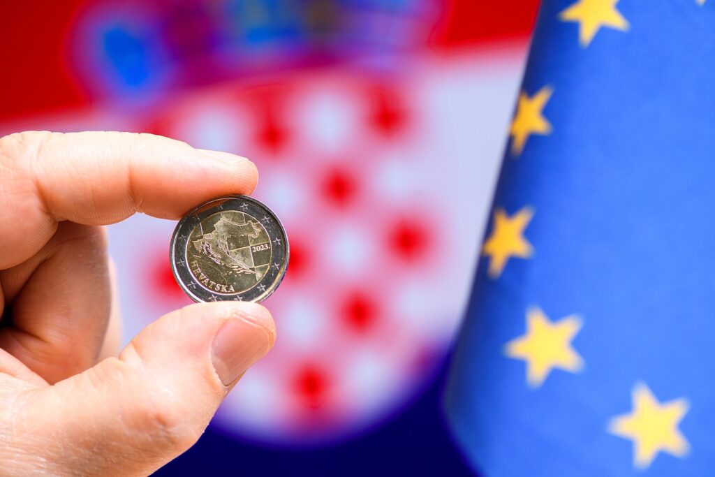 Banconote e monete in euro appoggiate su un piano chiaro e riprese dall'alto