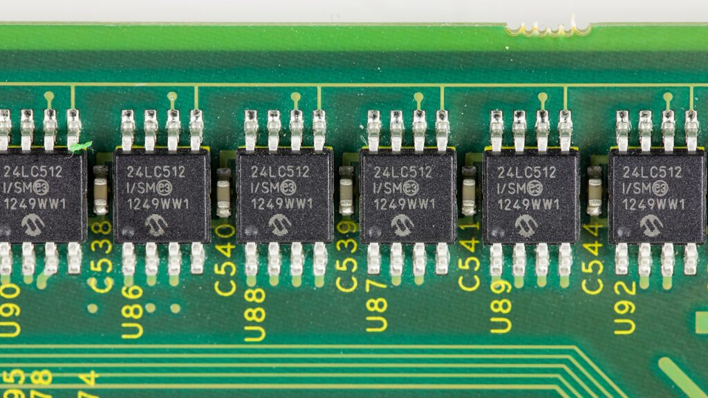 Microchip saldato su una scheda elettronica verde ripreso da vicino con le piste in evidenza