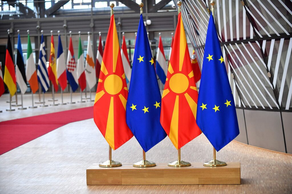 Bandiere dell'Unione europea esposte davanti a un edificio istituzionale in una giornata ventosa
