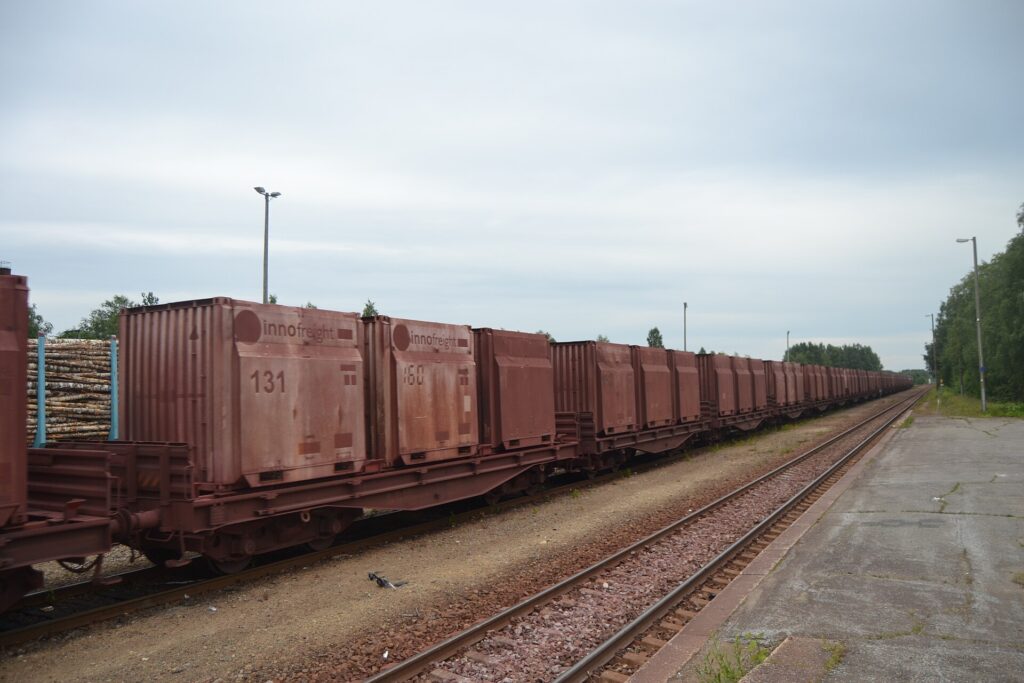 Treno merci carico di container fermo su un binario in una zona industriale