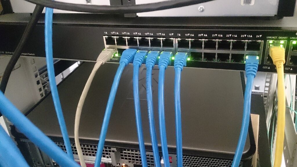 Cavi di rete colorati collegati alle porte di uno switch dentro un armadio tecnico