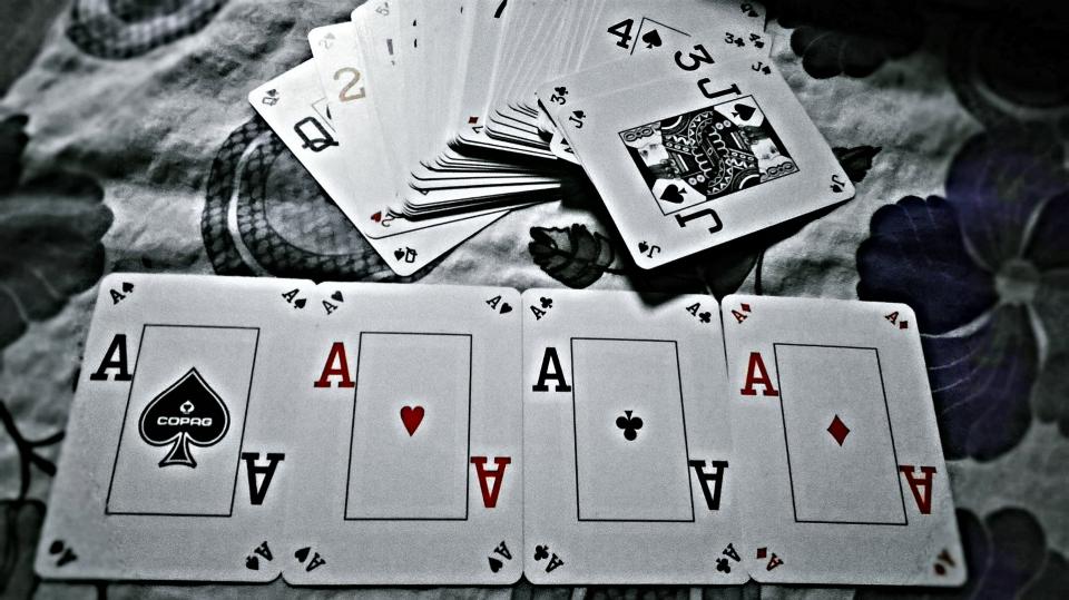 Carte da gioco sparse e mescolate sopra un tavolo di legno scuro