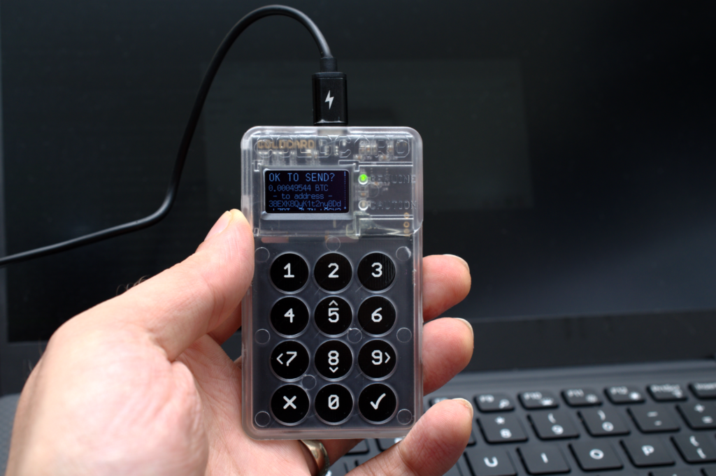 Piccolo dispositivo di firma con schermo acceso appoggiato su un tavolo di legno chiaro