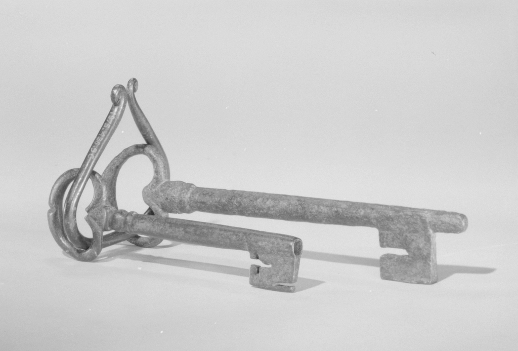 Mazzo di chiavi metalliche appoggiato sul piano di un tavolo di legno chiaro