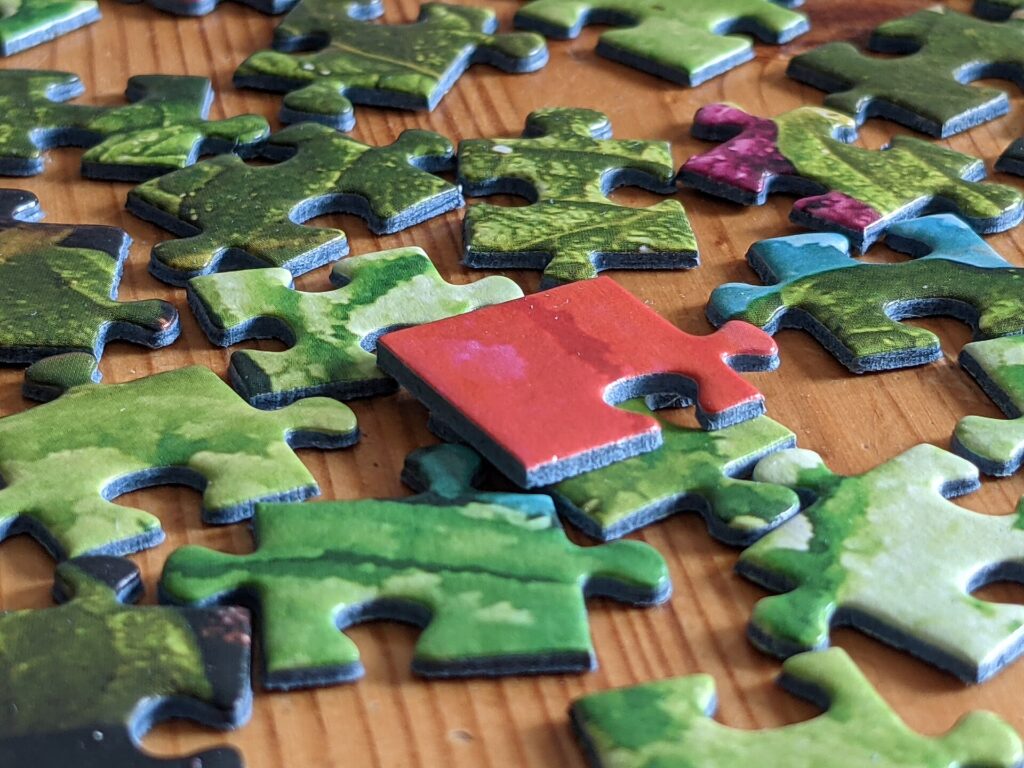 Tessere di un puzzle di cartone sparse su un tavolo con alcune già incastrate fra loro