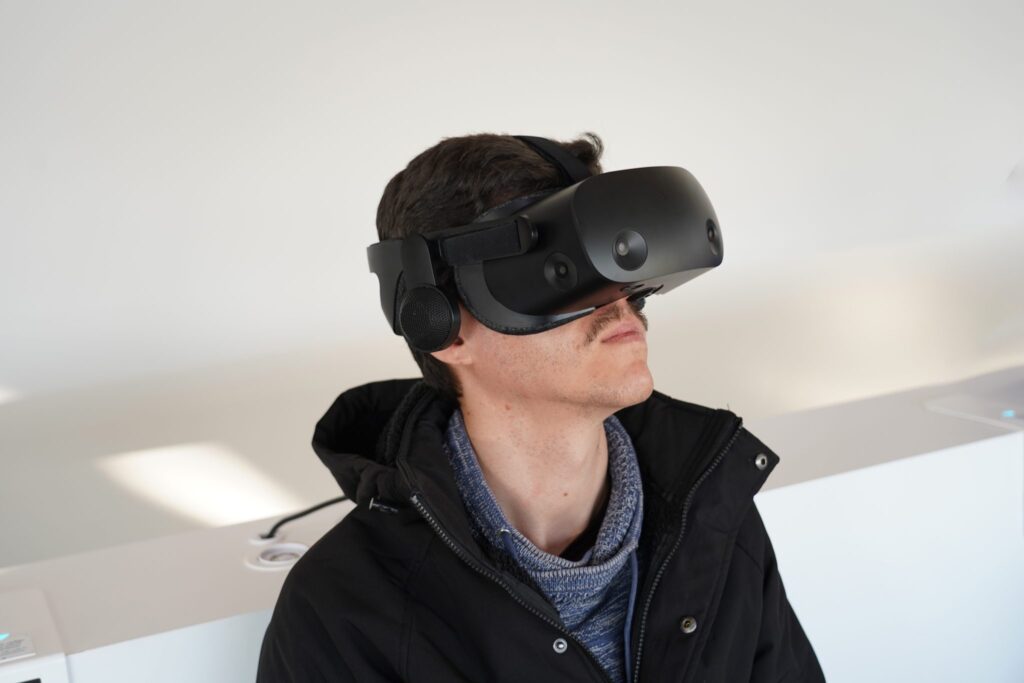 Persona seduta che indossa un visore per la realtà virtuale in una stanza illuminata