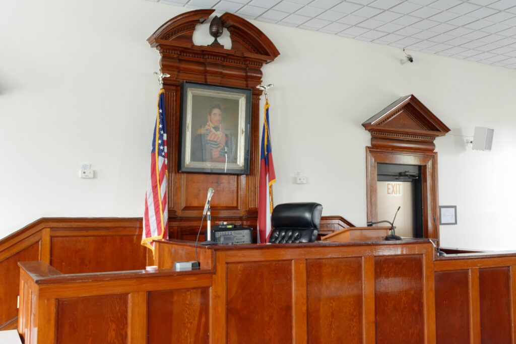 Banco di legno di un'aula di tribunale con sedie vuote e pareti in penombra